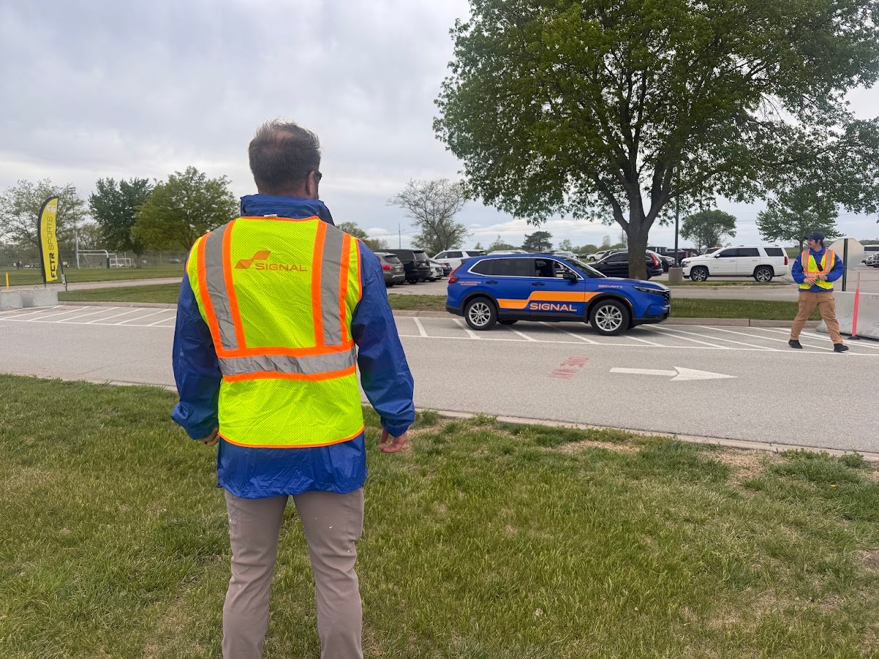 Signal of Lincoln officers directing event traffic beside a marked Signal patrol vehicle at the Lincoln Sports Foundation Sports Complex